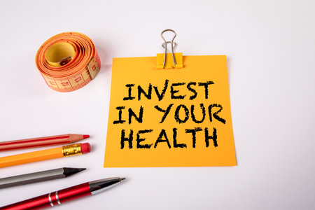 Invest in your health. Measuring tape and notepad with text on a white backgroundの写真素材