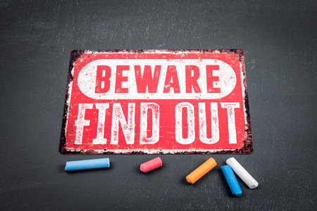 Find Out. Beware sign with text and colored pieces of chalk on a dark chalkboard backgroundの写真素材