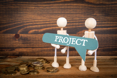 Project Concept. Green speech bubble with text and two miniature human figures on a wooden backgroundの写真素材
