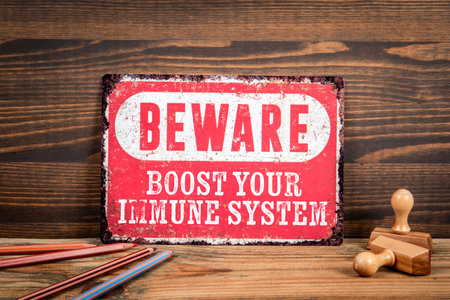 Boost your immune system. Beware sign with text on a wooden texture office tableの写真素材