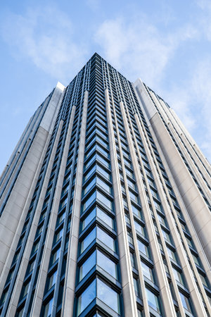Multi-storey building with windows, view from below, clouds in the skyの写真素材