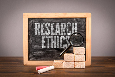 Research ethics. Miniature chalkboard and magnifying glass on a wooden tableの写真素材