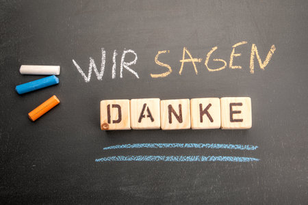 We say thank you. Text in german on a black chalkboard backgroundの写真素材