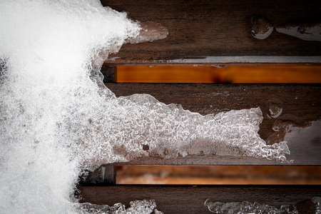 Spring and melting snow on a wooden texture backgroundの写真素材