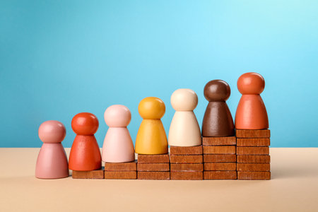 Wooden figures lined up on steps against a light background. A concept of competition and developmentの写真素材