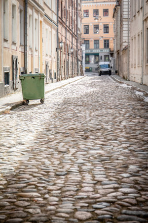 Cobblestone Street with Green Trash Bin and Historic Buildingsの写真素材