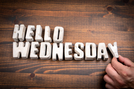 Hello Wednesday. Concrete alphabet letters and coffee mug on dark wooden texture backgroundの写真素材