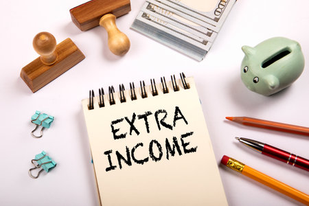 Extra Income Concept with Notebook, Money, Piggy Bank and Office Supplies on White Backgroundの写真素材