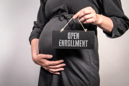 Pregnant Woman Holding Open Enrollment Sign Representing Healthcare Access and Maternity Benefitsの写真素材