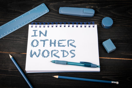 In Other Words. Notepad and blue stationery on a black wooden texture backgroundの写真素材