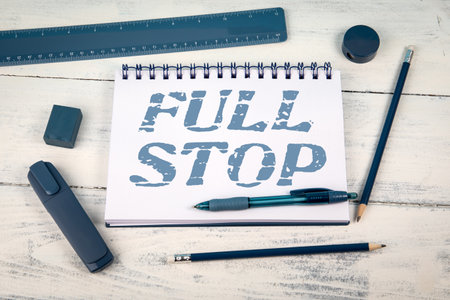 Full Stop Phrase Written on Notepad with Blue Stationery on White Wooden Backgroundの写真素材