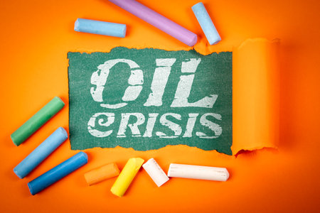 Oil Crisis Concept with Torn Paper and Colorful Chalk on Orange Backgroundの写真素材