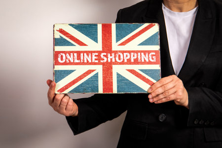 Online Shopping Sign with Union Jack Design Held by Person in Business Suitの写真素材