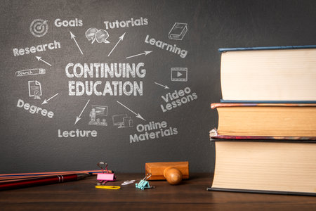 Continuing Education Concept with Chalkboard, Books, and Office Supplies on Wooden Deskの写真素材