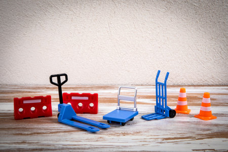 Miniature Warehouse Equipment and Safety Cones Displayed on Wooden Surface Against Neutral Wallの写真素材