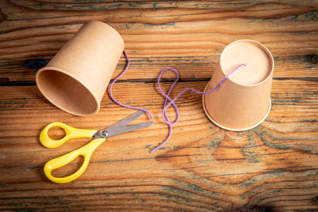Homemade Paper Cup Phone with String and Scissors on Wooden Table DIY Craftの写真素材