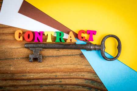 Contract agreement concept with colorful letters and vintage key on wooden deskの写真素材