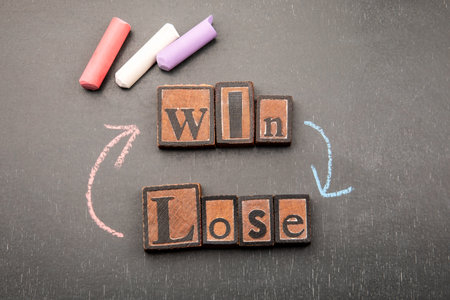 Win or lose concept with wooden block letters and chalk arrows on blackboardの写真素材