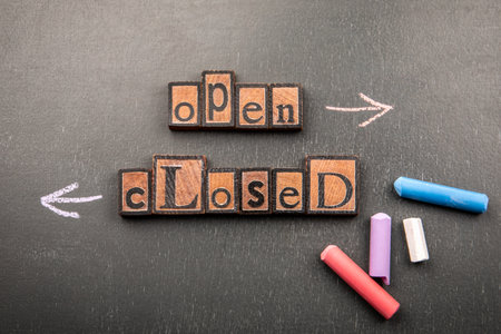 Open or closed concept with wooden letter blocks and chalk arrows on blackboardの写真素材