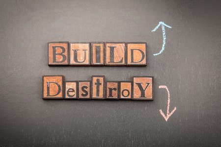 Build versus destroy concept with vintage wooden letter blocks and chalk arrows on blackboard