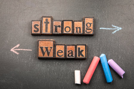 Chalk arrows being drawn step by step to illustrate the contrast between Strong and Weak concepts on a blackboard backgroundの写真素材