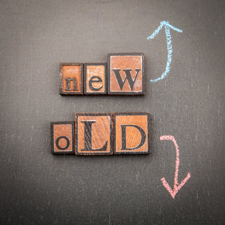 New versus old concept with wooden blocks and chalk arrows on blackboard background