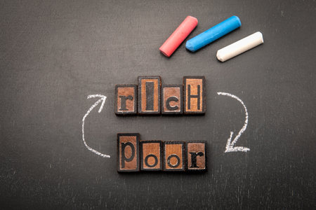 Rich and poor concept with wooden letter blocks and chalk arrows on blackboard