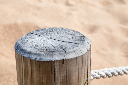 Weathered Wooden Post with Rope Fence on Sandy Beach in Bright Sunlight