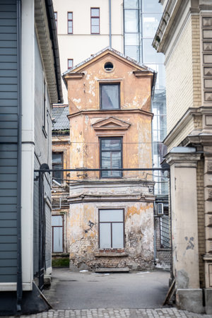 Dilapidated Old Building Between Modern Architecture in City Alleyの写真素材