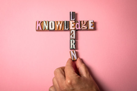 Knowledge and Learn concept on a pink background, with a hand placing the final letter