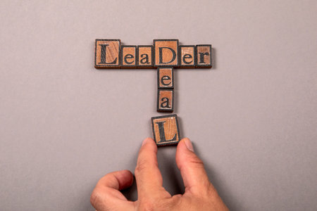 Wooden block letters spelling LEADER and DEAL in crossword style on gray background
