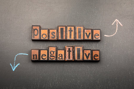 Positive and Negative with wooden letter blocks on blackboard and chalk arrows pointing up and downの写真素材