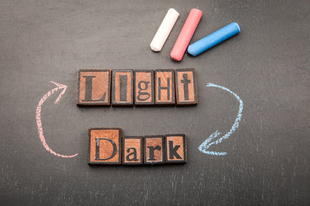 Light and Dark with wooden letter blocks on blackboard and chalk arrows connecting both directionsの写真素材