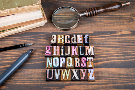 Alphabet concept with colorful wooden block letters arranged on wooden desk alongside books