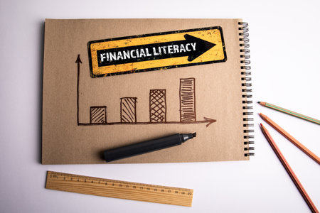 Financial literacy concept with notebook showing bar graph and yellow arrow sign with textの写真素材