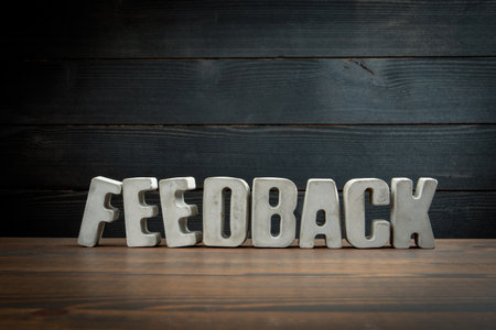 Word Feedback displayed in concrete block letters on wooden desk. Symbolizing communication,...