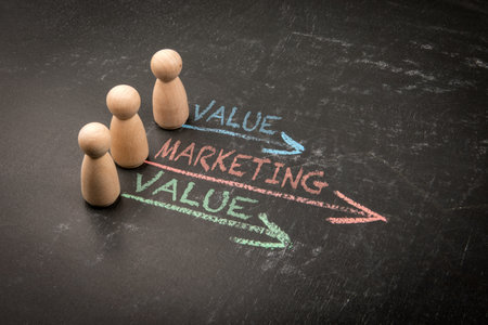Wooden figurines on a blackboard with chalk arrows pointing to words Value and Marketingの写真素材