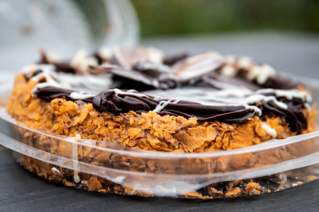 Close-up of chocolate cake with cream topping and crunchy crust in container