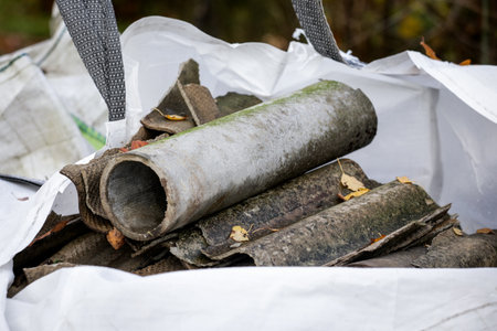 Asbestos Cement Pipes and Roofing Waste in a white construction bag. Hazardous material disposal and environmental safetyの写真素材