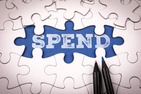 Word spend written on blue background under white puzzle piecesの写真素材