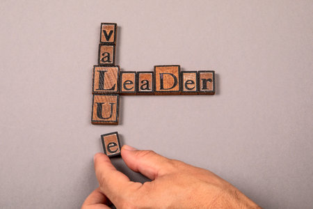 Words leader and value made from vintage wooden letterpress blocks with human hand arranging lettersの写真素材