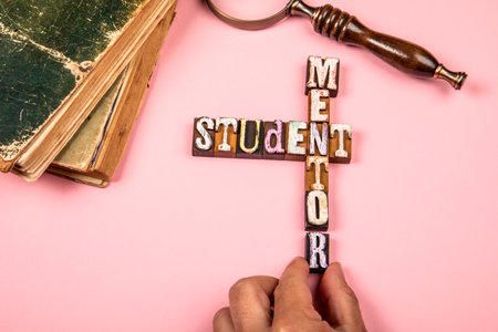 Words mentor and student made from vintage wooden letterpress blocks arranged in cross shape with old booksの写真素材