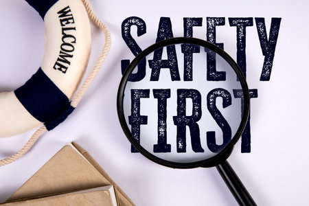 Magnifying Glass Focusing on Text Safety First with Symbol Representing Caution and Workplace Protection Conceptの写真素材