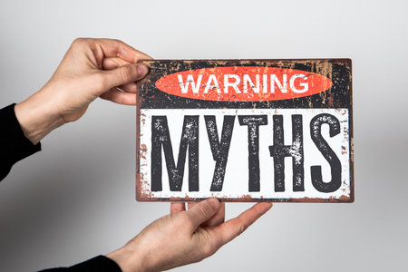 Vintage Warning Sign with the Word Myths Held by Hands on Neutral Backgroundの写真素材