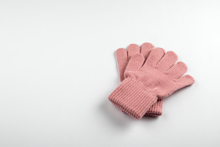A pair of soft pink wool gloves placed on a white background. Warmth, comfort and protection during the cold seasonの写真素材