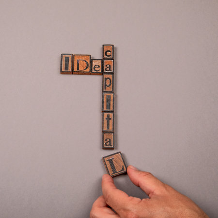 Idea Capital Concept with Wooden Letter Blocks and Hand on Gray Backgroundの写真素材