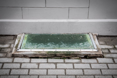 Old Basement Window Covered with Dirty Glass and Concrete Frameの写真素材