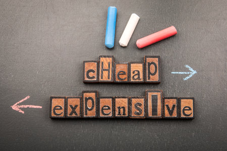 Cheap vs Expensive Concept with Wooden Letter Blocks and Chalk Arrows on Blackboard