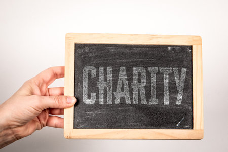 CHARITY Concept Displayed On Chalkboard Held By Human Handの写真素材