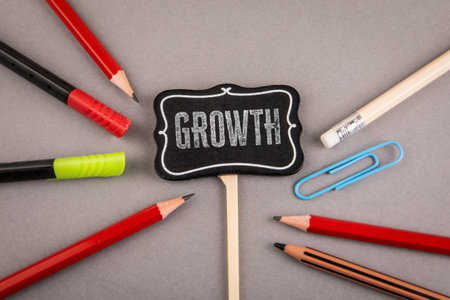 Growth Concept Displayed on Blackboard Sign Surrounded by School Supplies on Desk